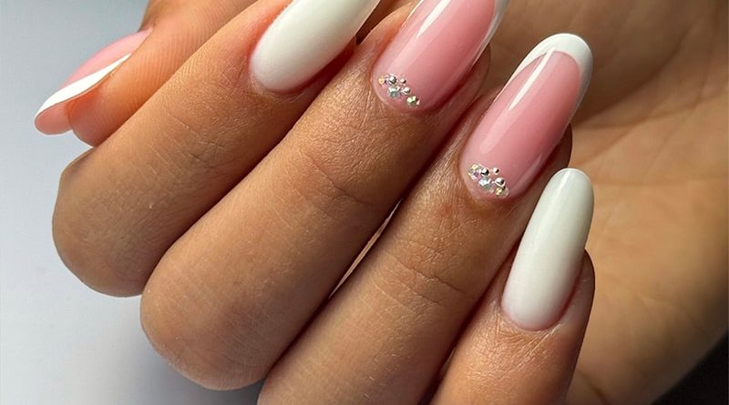 Pose ongulaire French Crystal avec French blanche et cristaux argentés en accent, sur ongles longs.