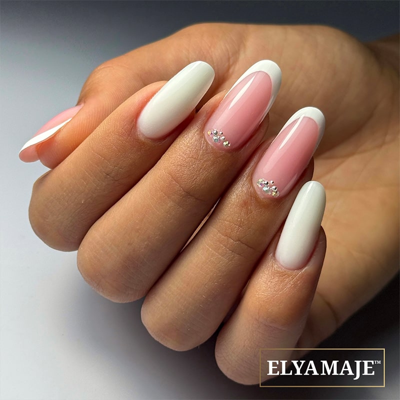 Pose ongulaire French Crystal avec French blanche et cristaux argentés en accent, sur ongles longs.