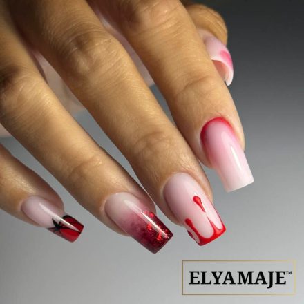 Main avec manucure rouge Halloween, incluant un nail art citrouille sur le petit doigt, un dégradé rouge, des motifs sanglants en relief et des traces de sang sur le pouce.